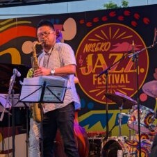 a young man playing saxaphone at a festival