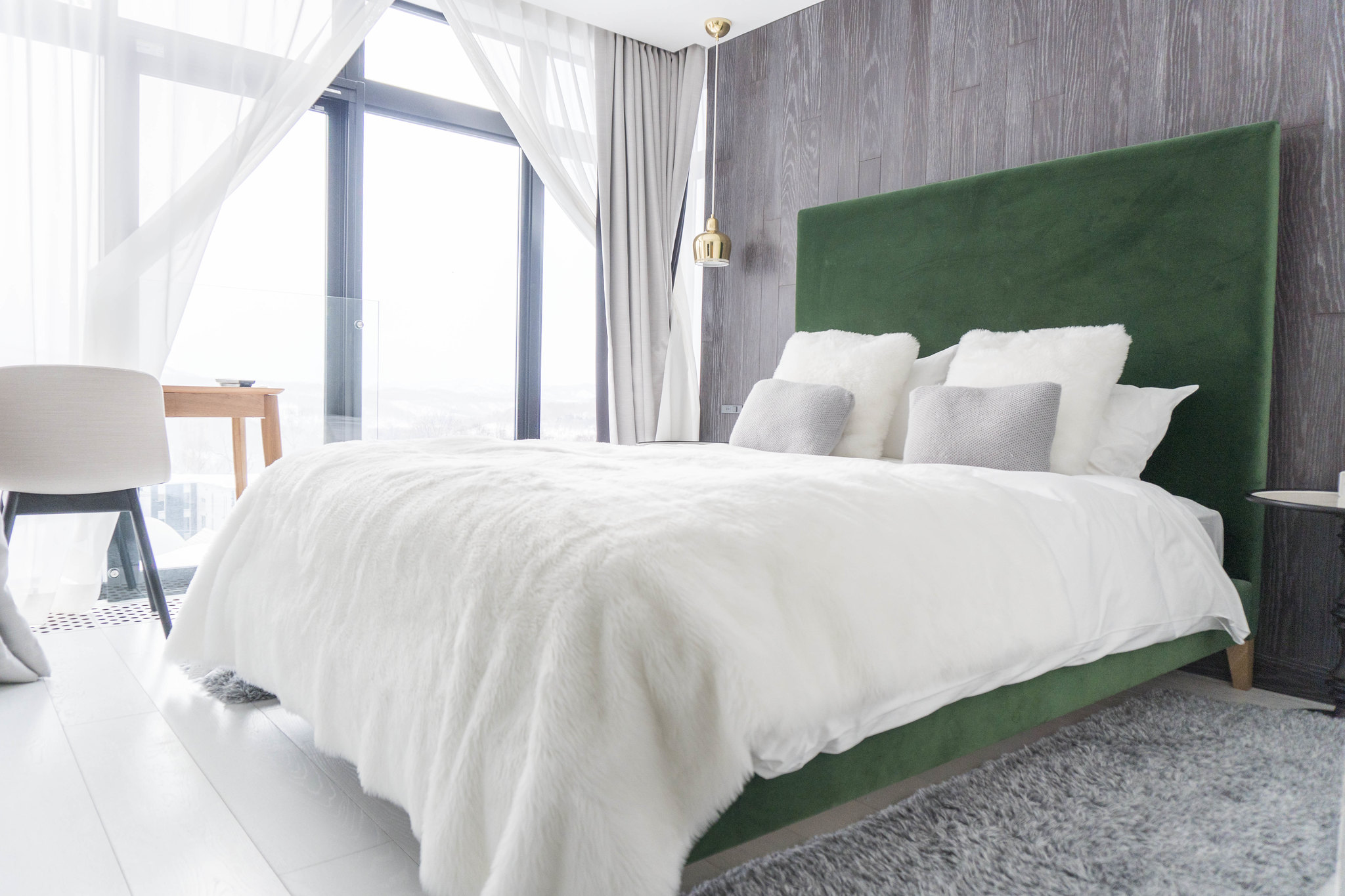 A plush queen bed with green backboard in a warm bedroom in LOFT Niseko.