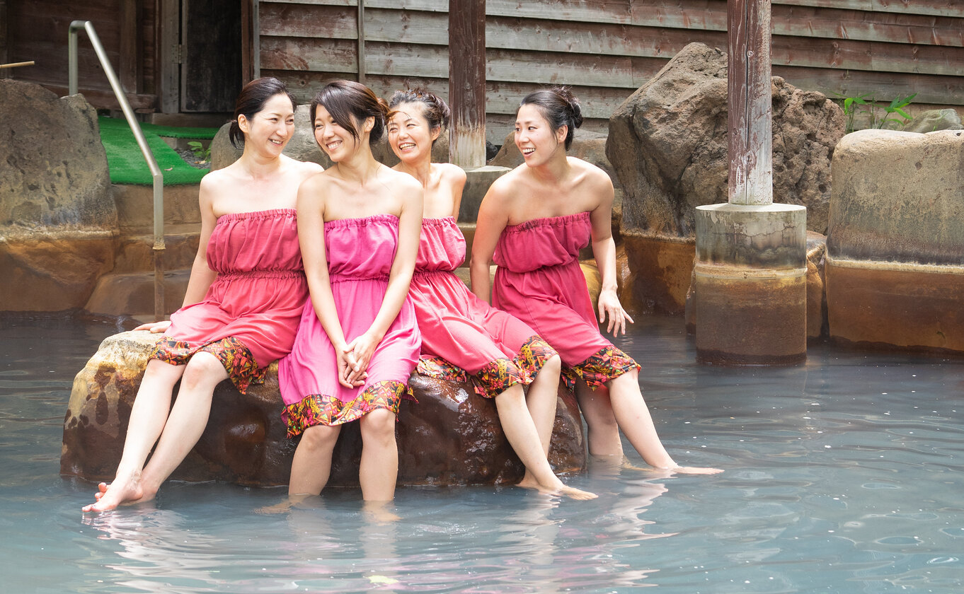 A group of 4 women wearing modesty dresses in a mixed onsen at Niseko Grand Hotel.